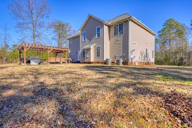 rear view of house featuring a jacuzzi, a pergola, a lawn, and central air condition unit