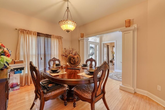 dining room featuring ornate columns, plenty of natural light, and light wood-type flooring