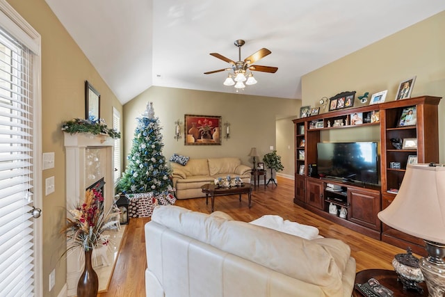 living room featuring light hardwood / wood-style flooring, vaulted ceiling, and ceiling fan