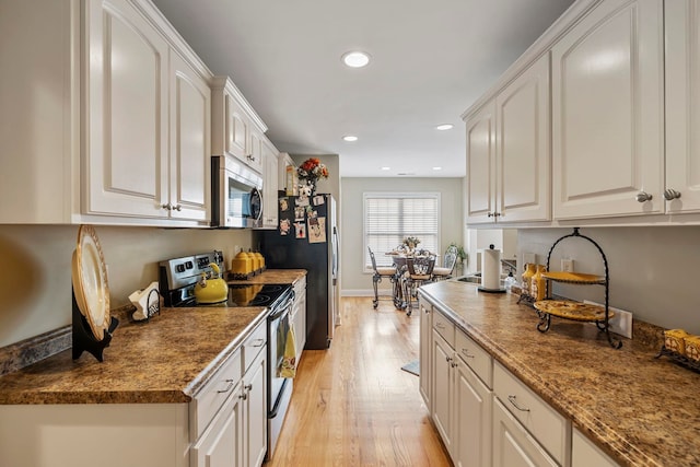 kitchen with light hardwood / wood-style flooring, white cabinets, and appliances with stainless steel finishes