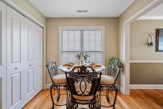 dining room with light hardwood / wood-style flooring and crown molding