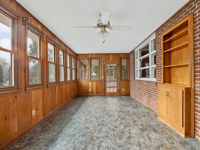 unfurnished sunroom featuring ceiling fan