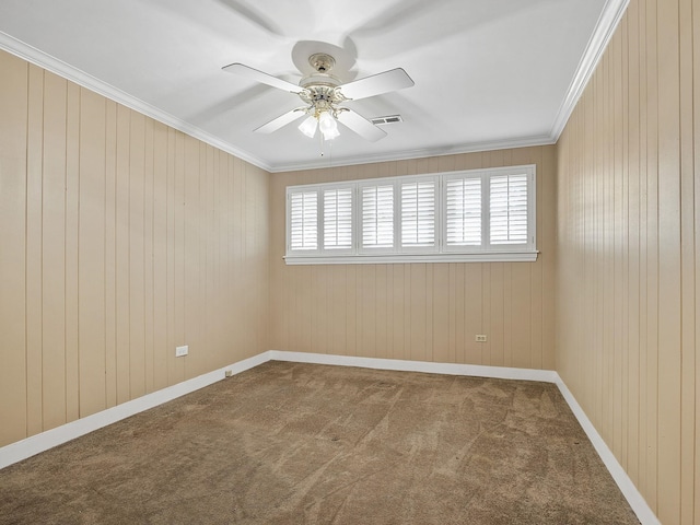 empty room with ceiling fan, wooden walls, carpet floors, and ornamental molding