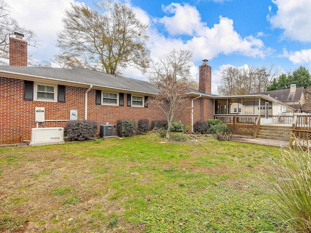 back of house with central air condition unit, a wooden deck, and a yard