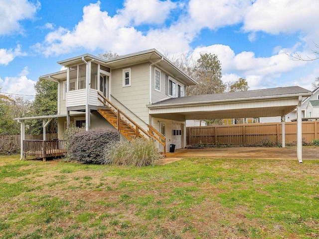 rear view of property with a lawn, a sunroom, and a carport