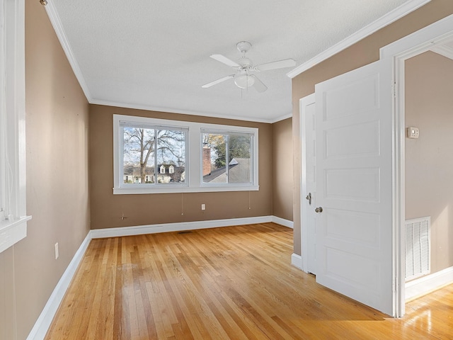 empty room featuring a textured ceiling, ceiling fan, light hardwood / wood-style floors, and crown molding