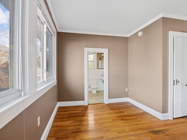 unfurnished bedroom with connected bathroom, crown molding, a textured ceiling, and light wood-type flooring