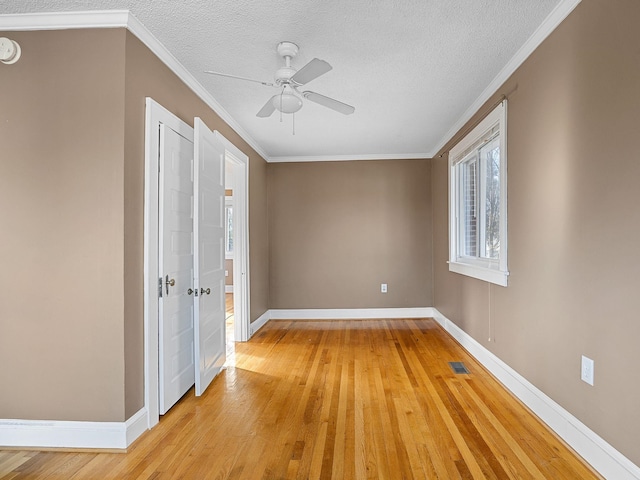 unfurnished room with ceiling fan, crown molding, a textured ceiling, and light hardwood / wood-style flooring