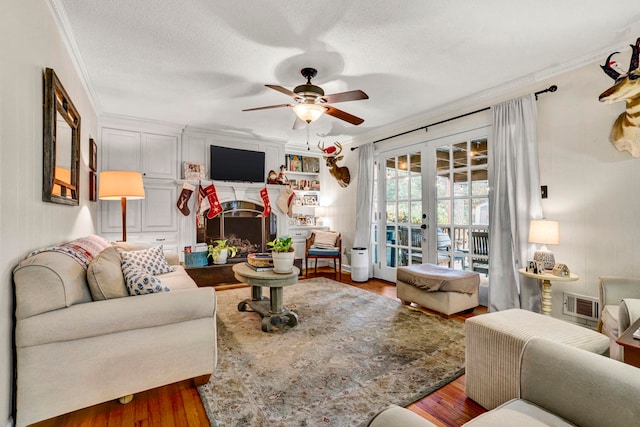 living room with french doors, hardwood / wood-style flooring, ceiling fan, ornamental molding, and a textured ceiling