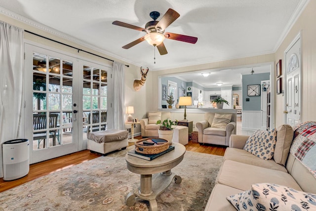 living room with french doors, ornamental molding, a textured ceiling, ceiling fan, and light hardwood / wood-style flooring