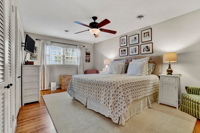 bedroom with ceiling fan, a textured ceiling, and light wood-type flooring