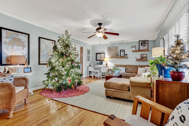 living room with a textured ceiling, hardwood / wood-style flooring, ceiling fan, and ornamental molding