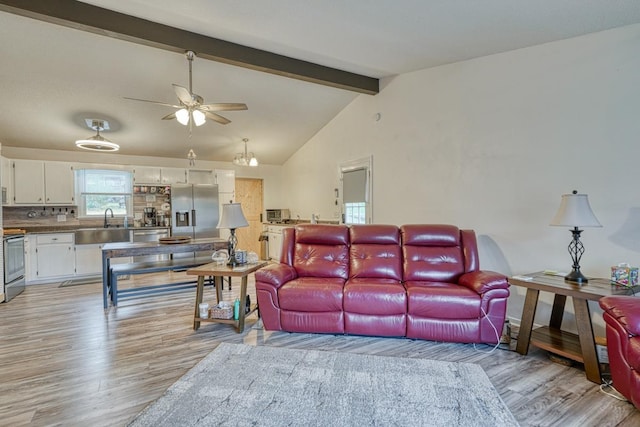 living room featuring lofted ceiling with beams, light hardwood / wood-style flooring, ceiling fan, and sink