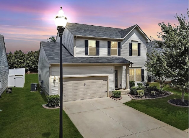 view of front of home featuring a garage, central AC unit, and a lawn