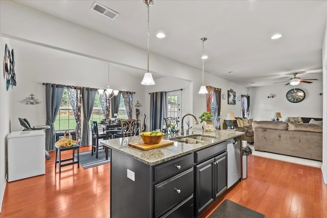 kitchen featuring pendant lighting, plenty of natural light, sink, and an island with sink