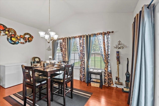 dining space with wood-type flooring, vaulted ceiling, and a notable chandelier