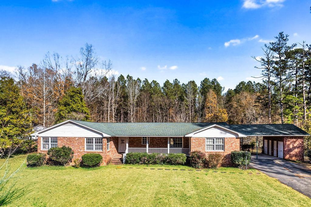 ranch-style home featuring a front lawn, a porch, and a carport