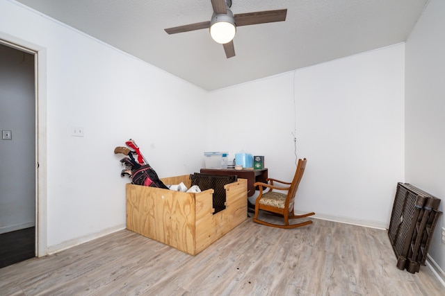 living area with ceiling fan, hardwood / wood-style floors, and a textured ceiling