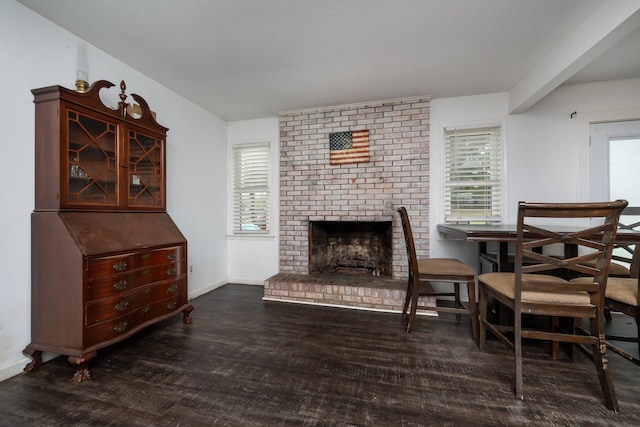 dining room featuring a brick fireplace and dark wood-type flooring