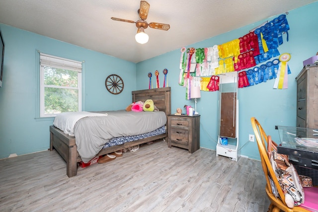 bedroom featuring ceiling fan, light wood-type flooring, and a textured ceiling