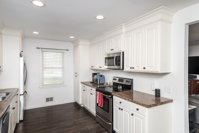 kitchen featuring white cabinetry, sink, stainless steel appliances, dark hardwood / wood-style floors, and dark stone countertops