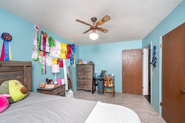 bedroom featuring ceiling fan, light hardwood / wood-style floors, and a textured ceiling