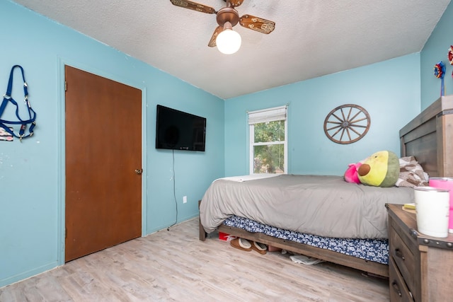 bedroom with ceiling fan, light hardwood / wood-style flooring, and a textured ceiling