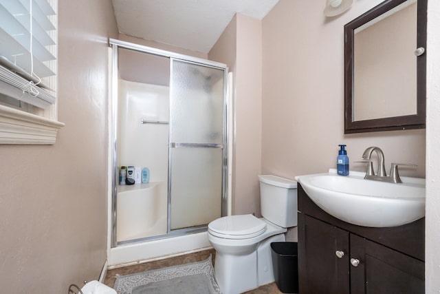 bathroom with a textured ceiling, vanity, toilet, and a shower with shower door