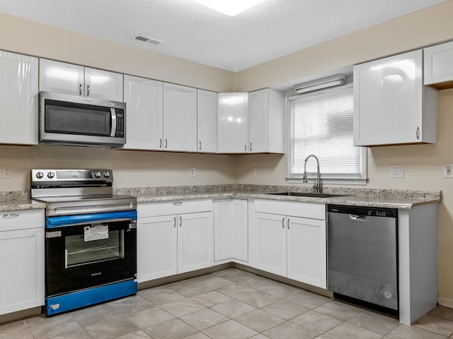 kitchen featuring a textured ceiling, sink, white cabinetry, and stainless steel appliances