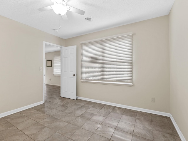 tiled spare room featuring a textured ceiling and ceiling fan