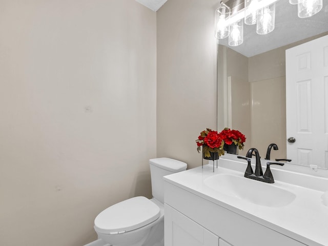 bathroom featuring vanity, toilet, and a textured ceiling