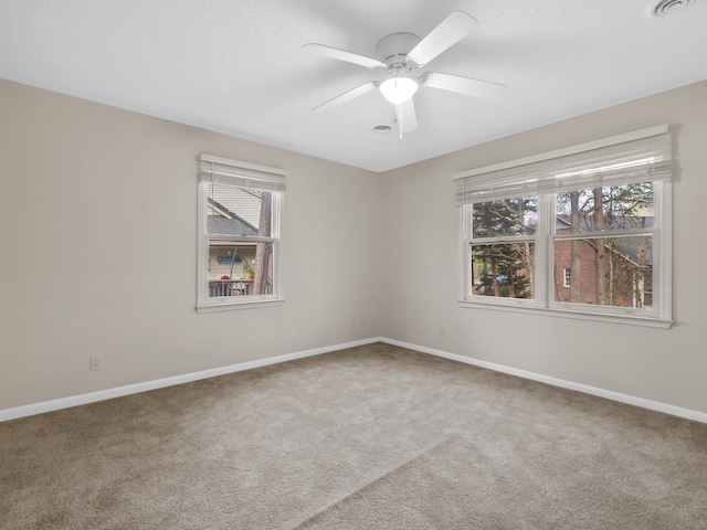 carpeted spare room with a wealth of natural light and ceiling fan