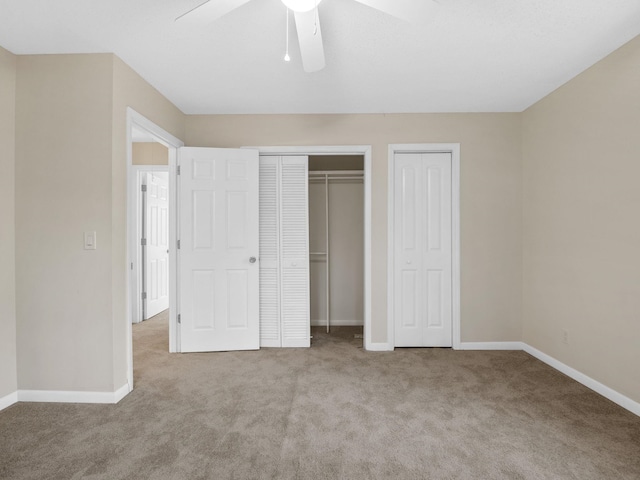 unfurnished bedroom featuring ceiling fan, light colored carpet, and multiple closets