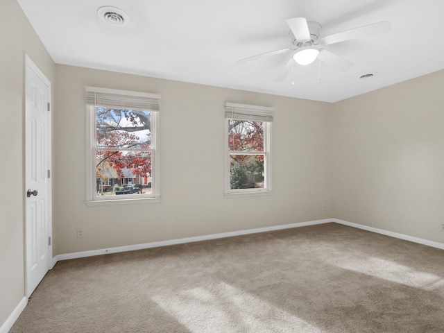 empty room featuring carpet flooring, ceiling fan, and a wealth of natural light