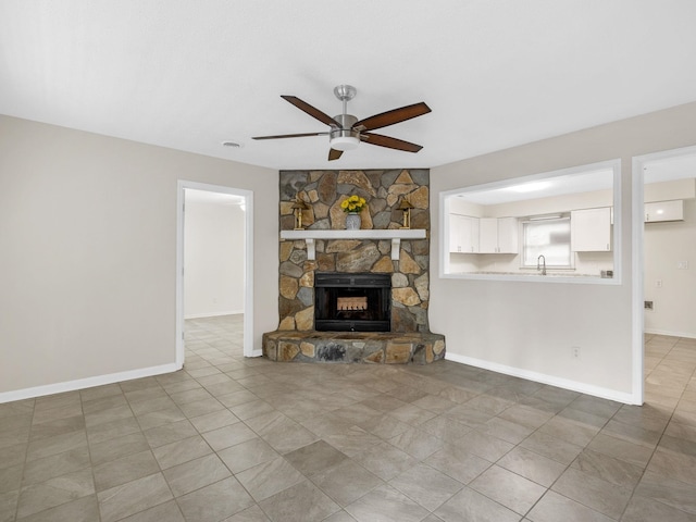 unfurnished living room with a fireplace, ceiling fan, and sink