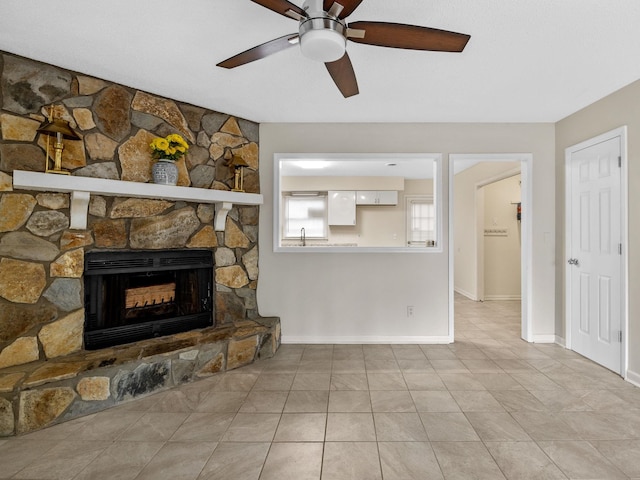 tiled living room with ceiling fan and a stone fireplace