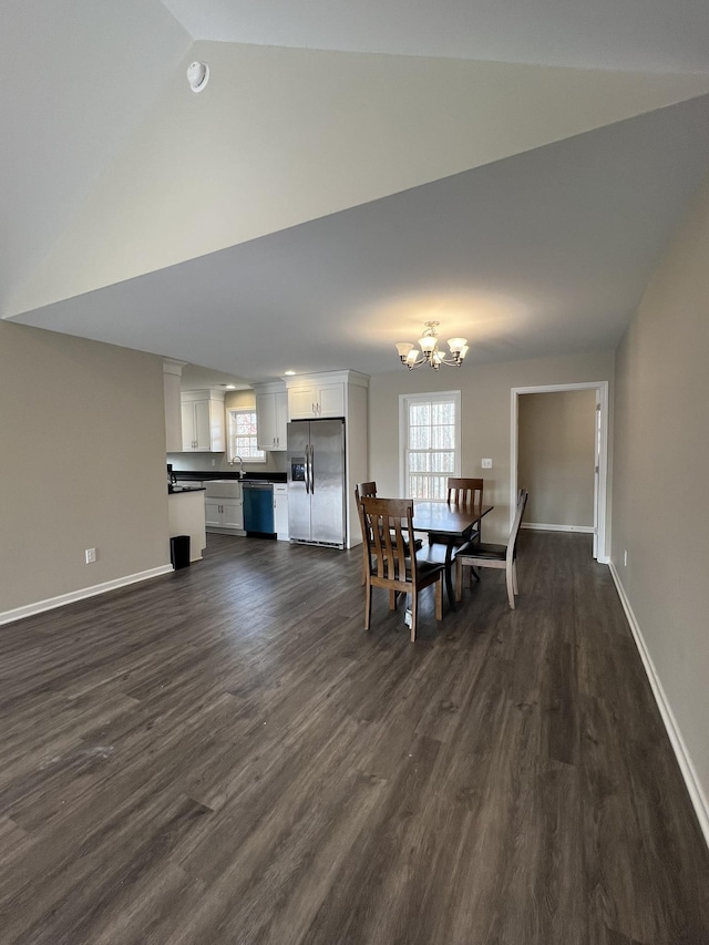 dining space featuring a chandelier, sink, dark wood-type flooring, and vaulted ceiling