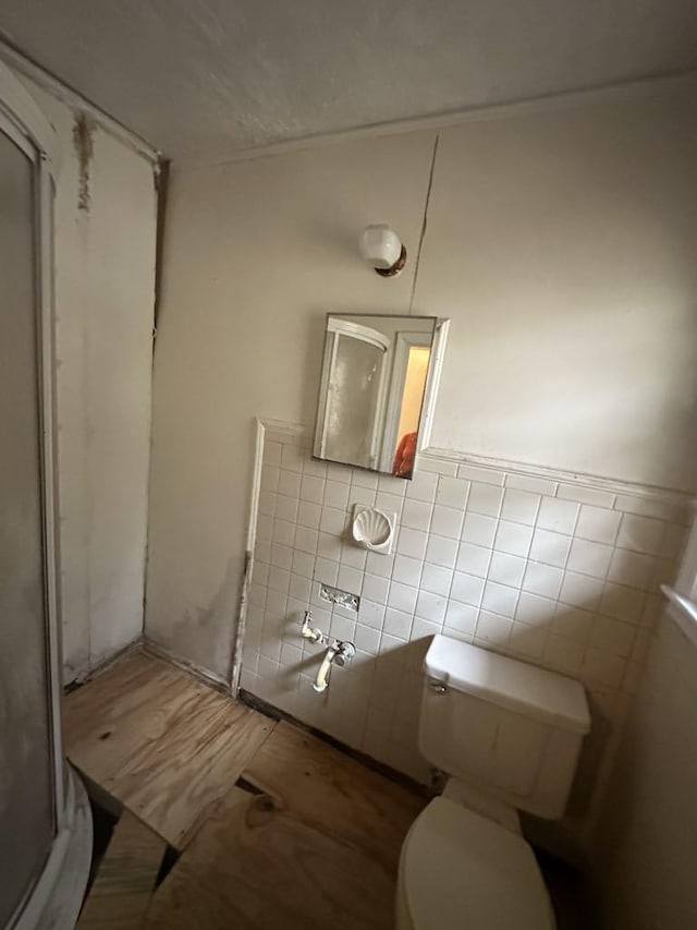 bathroom with walk in shower, toilet, and tile walls