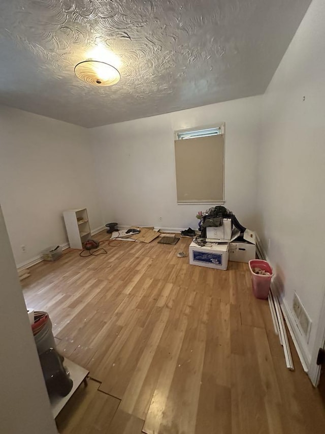 spare room featuring light hardwood / wood-style floors and a textured ceiling