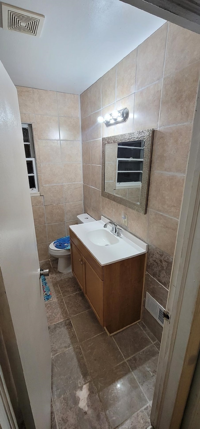 bathroom featuring tile walls, vanity, decorative backsplash, and toilet