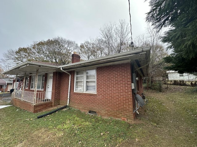 view of side of property with covered porch and a lawn