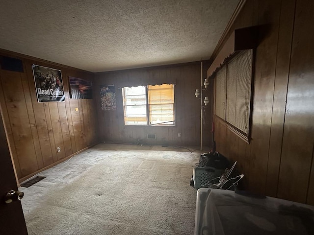 carpeted spare room featuring a textured ceiling and wood walls