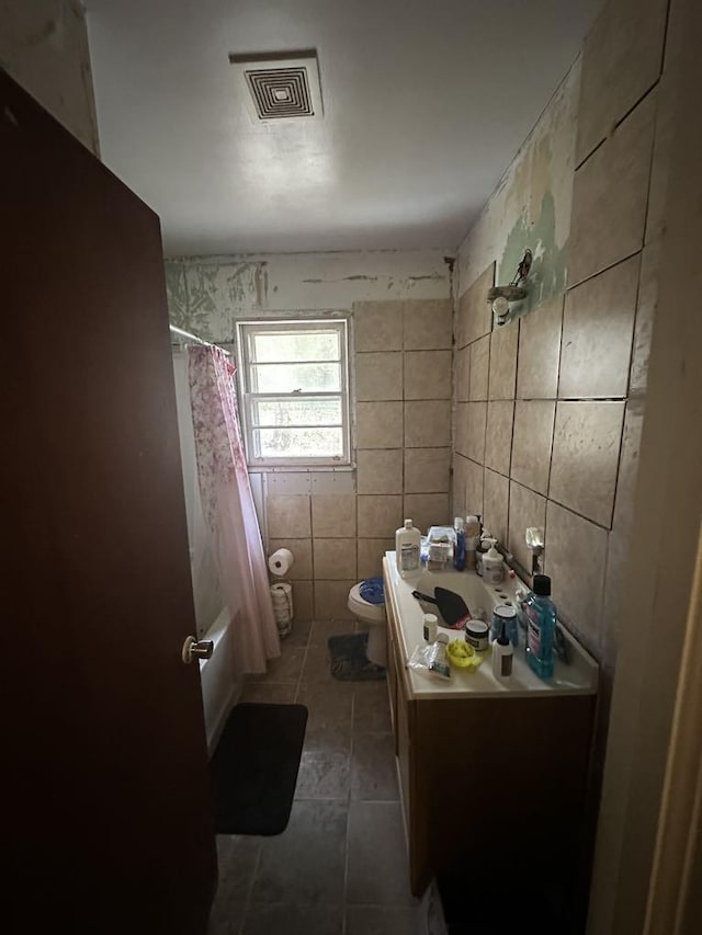 full bathroom with tile walls, vanity, shower / tub combo, and toilet