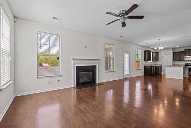 unfurnished living room with dark hardwood / wood-style flooring and ceiling fan with notable chandelier