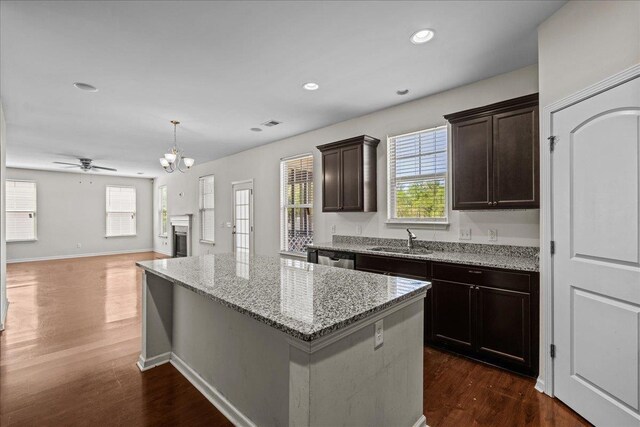 kitchen featuring sink, dark hardwood / wood-style floors, decorative light fixtures, a kitchen island, and ceiling fan with notable chandelier