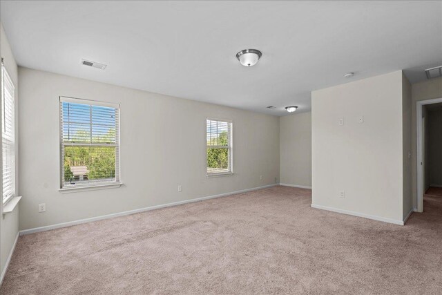 spare room with plenty of natural light and light colored carpet