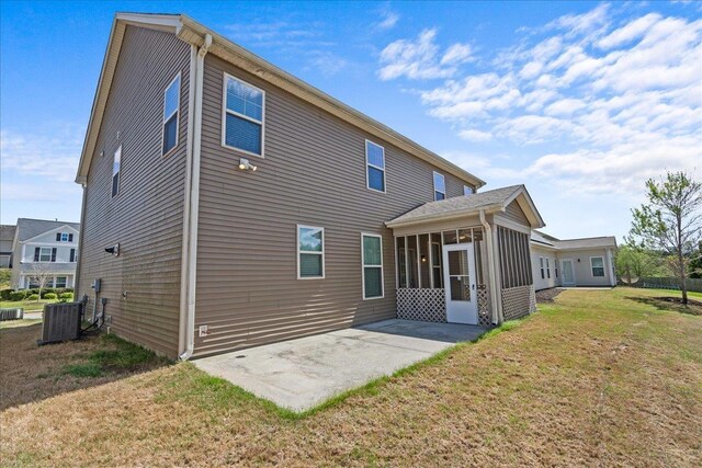 rear view of house with a sunroom, a yard, a patio, and central AC unit