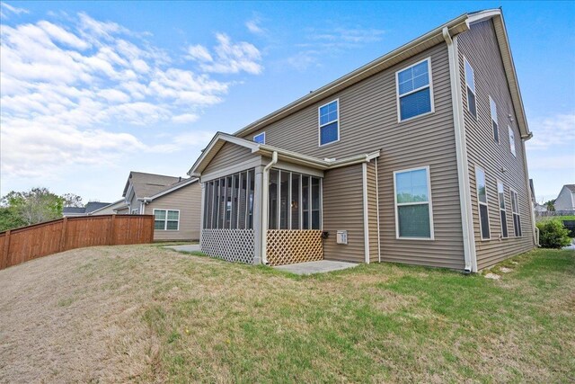 back of property with a sunroom and a yard