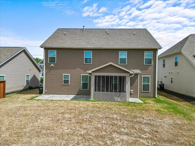 rear view of property featuring a sunroom, a patio area, and a lawn