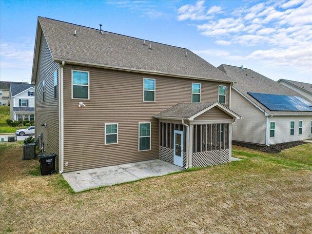 rear view of house with a patio area, a sunroom, a yard, and central AC